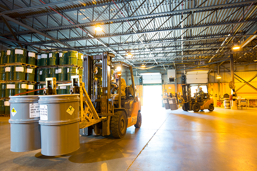 Workers move drums of uranium concentrates received from all over the world at the Blind River refinery.  